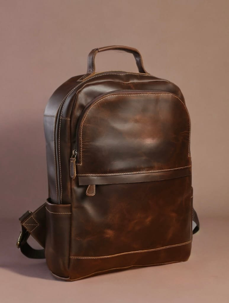 A brown genuine leather backpack with multiple compartments and brass-toned hardware, displayed against a neutral background.